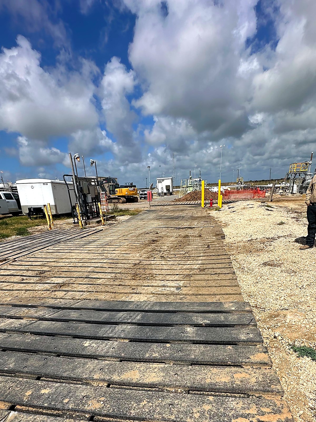 Recycled 3-ply mats forming a job-site road beside a crew member
