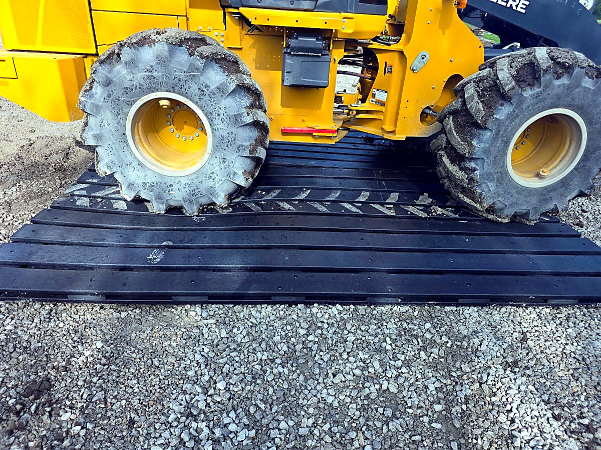 Loaded telehandler tires sitting on a recycled HDPE mat over gravel