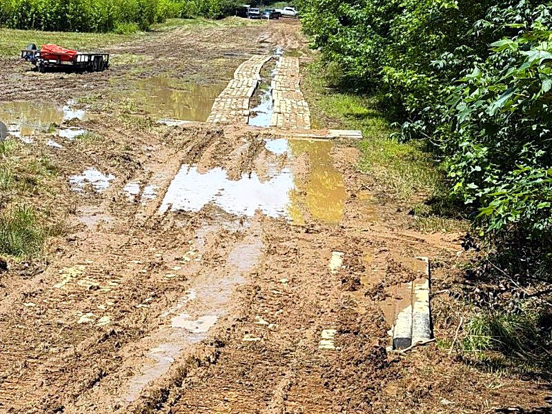 Rutted, waterlogged timber mat road sinking into mud